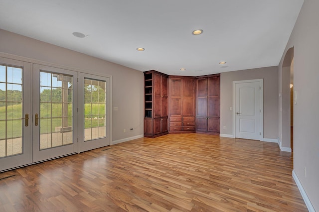 interior space with recessed lighting, baseboards, arched walkways, and light wood-type flooring