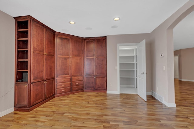 interior space with visible vents, arched walkways, and light wood finished floors