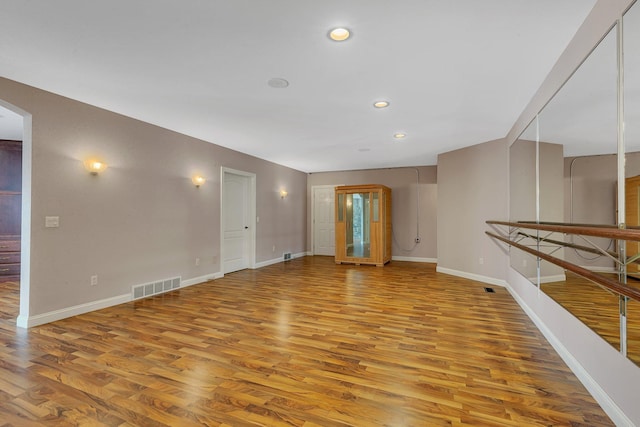 unfurnished living room featuring light wood finished floors, visible vents, arched walkways, and baseboards