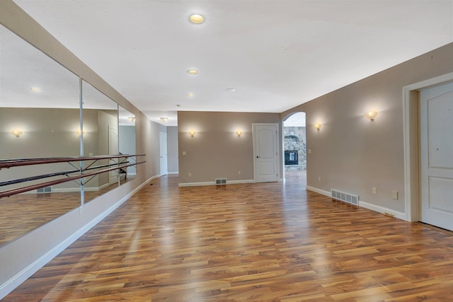 interior space with wood finished floors, visible vents, and arched walkways