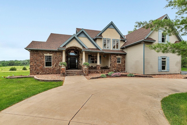 view of front of house featuring a front lawn, stucco siding, stone siding, and a shingled roof