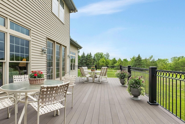 deck with outdoor dining space and a lawn