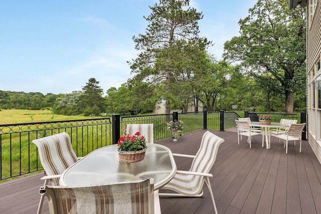 wooden terrace featuring outdoor dining area and a yard