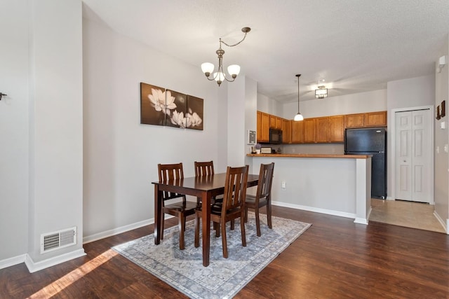 dining room with visible vents, baseboards, a notable chandelier, and dark wood-style floors