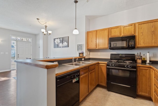 kitchen with a peninsula, a sink, black appliances, decorative light fixtures, and a chandelier