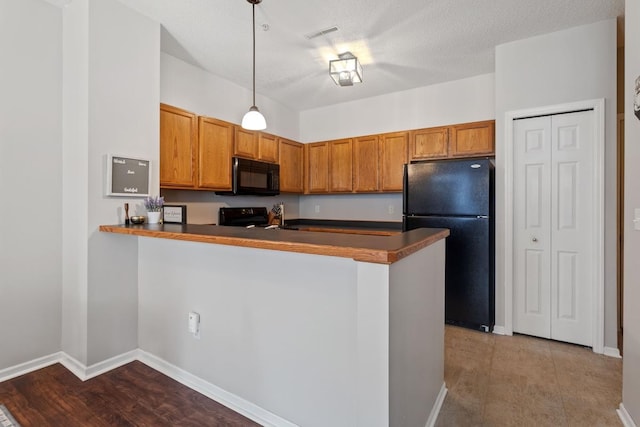 kitchen with dark countertops, black appliances, a peninsula, and brown cabinetry