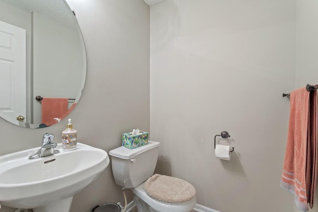 bathroom with a sink, baseboards, and toilet