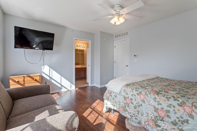 bedroom with visible vents, ensuite bath, wood finished floors, baseboards, and ceiling fan