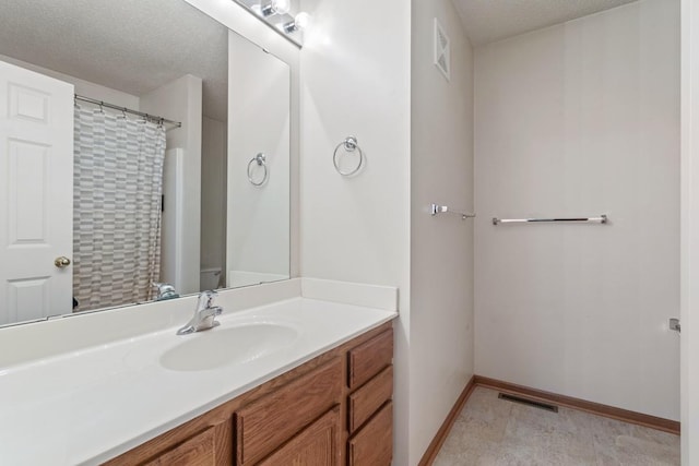 bathroom with visible vents, a textured ceiling, vanity, and baseboards