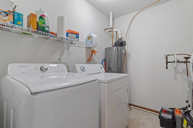 washroom with baseboards, water heater, laundry area, a textured ceiling, and separate washer and dryer