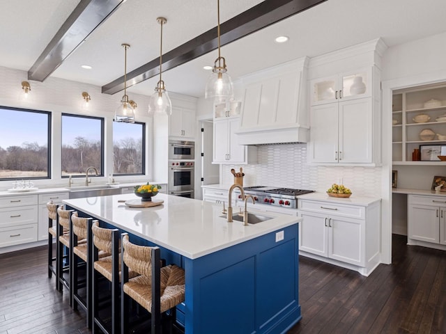 16419 Kiska St NE, Ham Lake, MN 55304 - kitchen with dark wood-style floors, beam ceiling, light countertops, a breakfast bar, and a kitchen island with sink