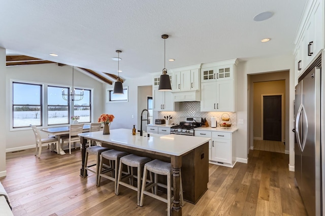 kitchen with stainless steel appliances, tasteful backsplash, an island with sink, and dark wood-style floors