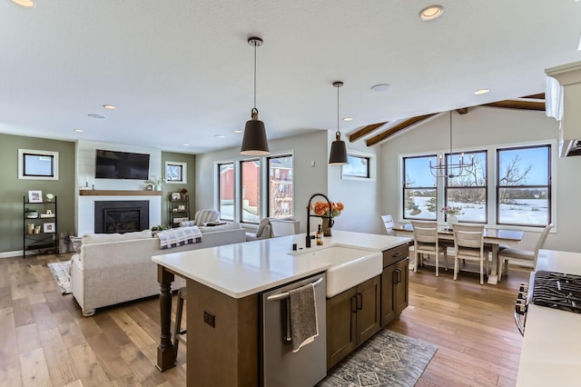 kitchen with a sink, dishwasher, light wood-style flooring, and light countertops