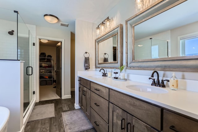 bathroom with a sink, visible vents, wood finished floors, and a shower stall