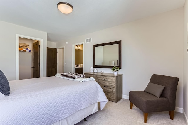 bedroom with a spacious closet, light colored carpet, visible vents, and baseboards