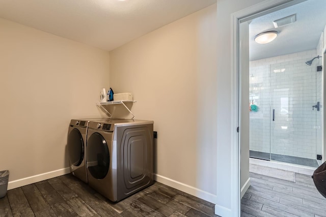 washroom with dark wood finished floors, laundry area, washer and dryer, and baseboards