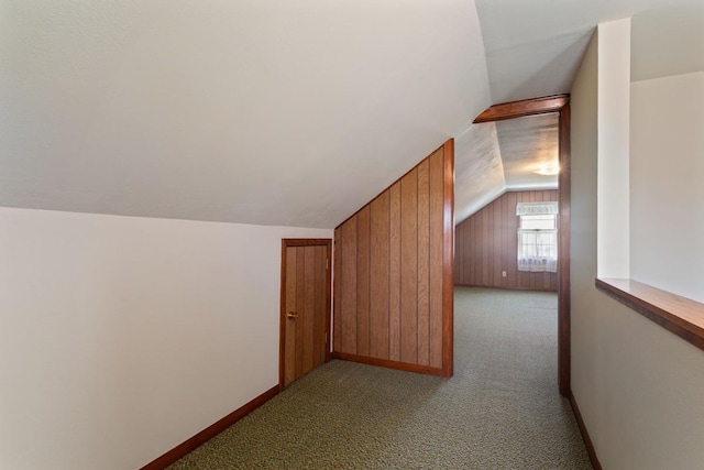 additional living space featuring vaulted ceiling, baseboards, wooden walls, and carpet floors