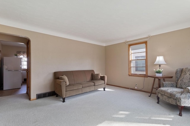 living room featuring baseboards, carpet, visible vents, and arched walkways