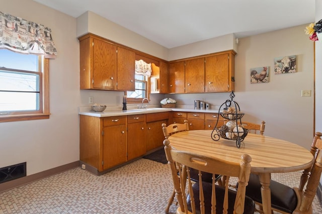 kitchen featuring visible vents, brown cabinets, light countertops, and a sink