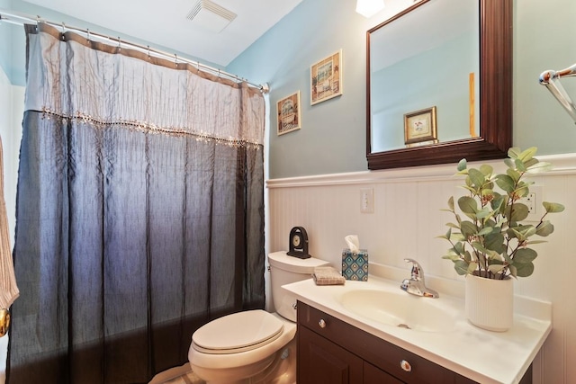 full bath with visible vents, curtained shower, a wainscoted wall, toilet, and vanity