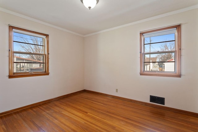 empty room with visible vents, baseboards, crown molding, and light wood-style floors