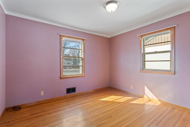 unfurnished room featuring visible vents, baseboards, and wood finished floors