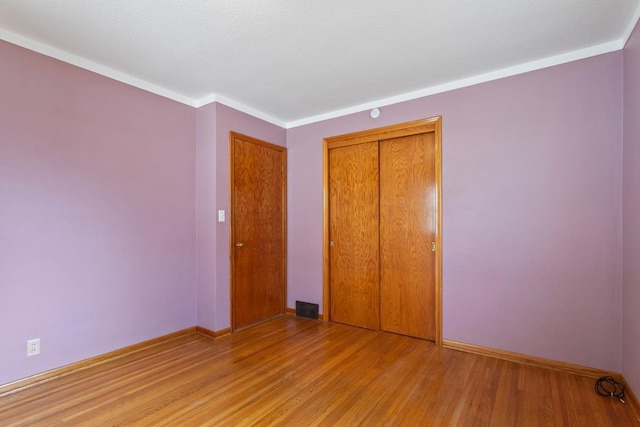 unfurnished bedroom with a closet, visible vents, light wood-style flooring, and baseboards