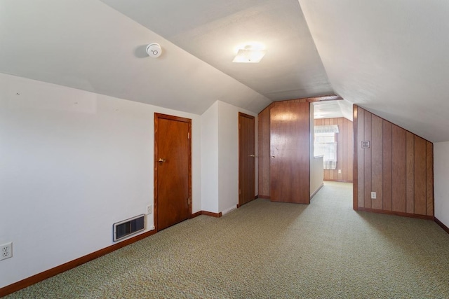 additional living space featuring lofted ceiling, light colored carpet, visible vents, and baseboards