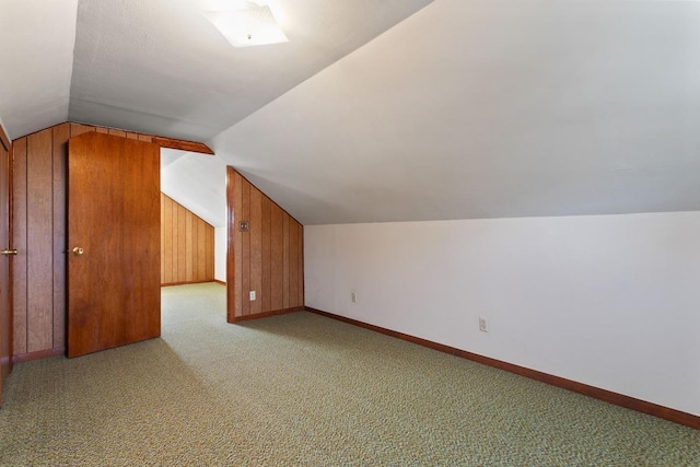 bonus room with carpet flooring, wood walls, baseboards, and vaulted ceiling