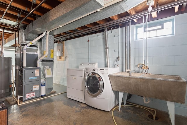 clothes washing area featuring gas water heater, electric panel, laundry area, washer and dryer, and a sink