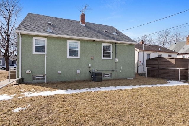 back of property with central air condition unit, stucco siding, a chimney, and roof with shingles