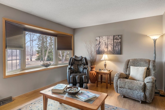 interior space with visible vents, a textured ceiling, and wood finished floors