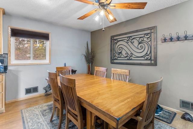 dining room featuring visible vents, baseboards, a textured ceiling, and light wood-style flooring