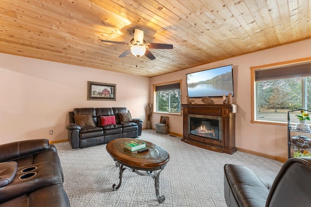 carpeted living area featuring a glass covered fireplace, baseboards, and wooden ceiling