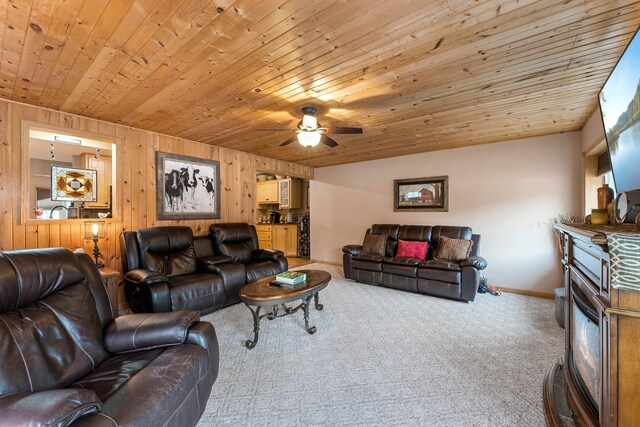 living room with wooden walls, baseboards, carpet flooring, wooden ceiling, and a ceiling fan