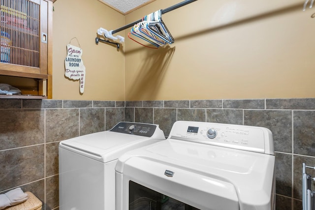 washroom with washing machine and clothes dryer, laundry area, and tile walls