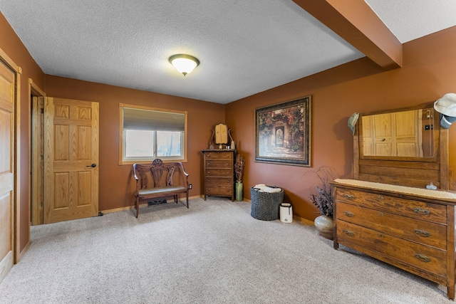 living area with beamed ceiling, baseboards, carpet, and a textured ceiling