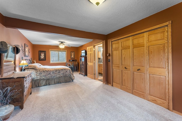 carpeted bedroom with beamed ceiling, a ceiling fan, a textured ceiling, ensuite bath, and a closet