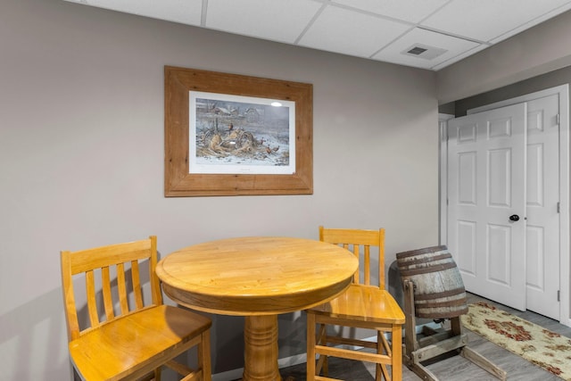 dining space featuring wood finished floors, visible vents, and a drop ceiling