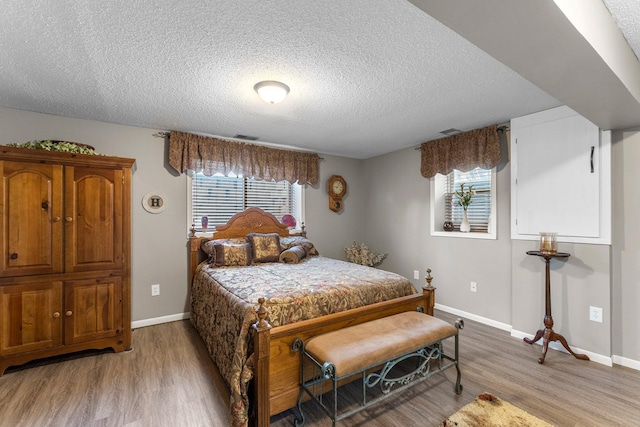 bedroom with light wood-style flooring, baseboards, and multiple windows