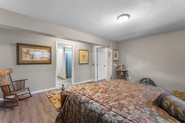 bedroom with baseboards, a textured ceiling, and wood finished floors