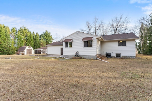 back of house with a storage unit, a lawn, central AC unit, and an outdoor structure