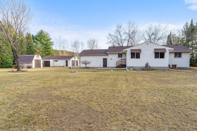 rear view of house with a storage unit, an outbuilding, a yard, and entry steps