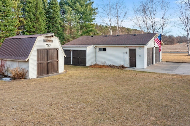 back of property with a gambrel roof, an outbuilding, a detached garage, a yard, and a storage shed