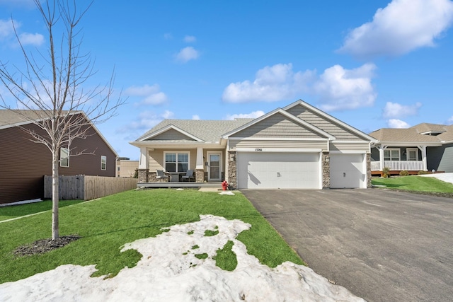 craftsman inspired home featuring fence, driveway, a porch, an attached garage, and a front lawn