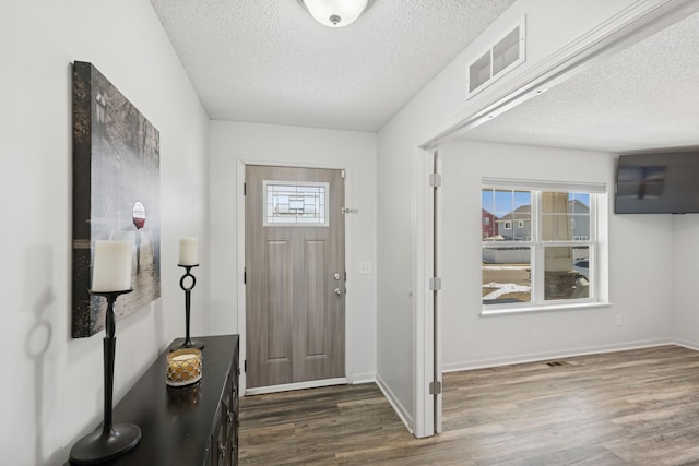 entryway with visible vents, a textured ceiling, and dark wood finished floors