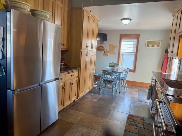 kitchen with dark stone countertops, baseboards, dark tile patterned floors, and freestanding refrigerator