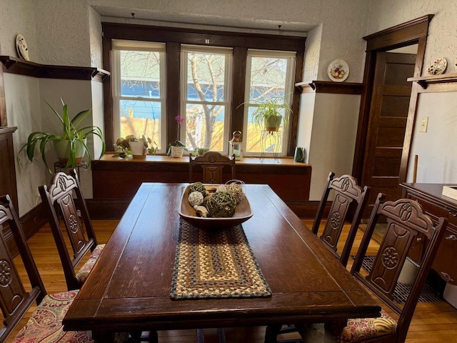 dining space with plenty of natural light, light wood-type flooring, and a textured wall