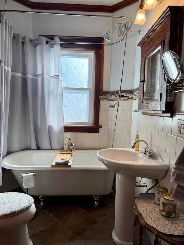 full bath featuring tile patterned floors, toilet, tile walls, and a tub to relax in