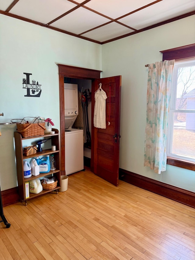 spare room featuring baseboards, stacked washer and dryer, and light wood finished floors